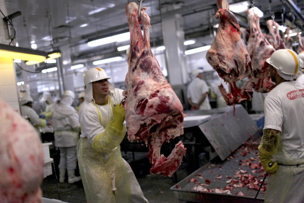 Workers process meat on a production line at the Minerva SA meat processing plant in Barretos, Brazil, on Tuesday, Aug. 20, 2012. Minerva SA, Brazil's third-largest beef producer, expects the company's net debt to fall to 2.5 times Ebitda in two years as beef plants ramp up. Photographer: Dado Galdieri/Bloomberg