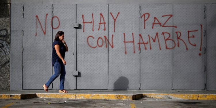 A woman walks in front of a graffiti that reads